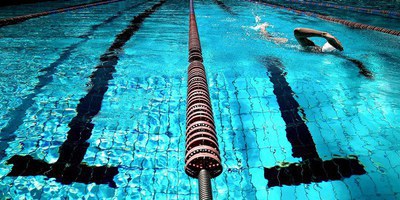 Foto eines Schwimmbeckens. In der Ecke sieht man einen Schwimmer